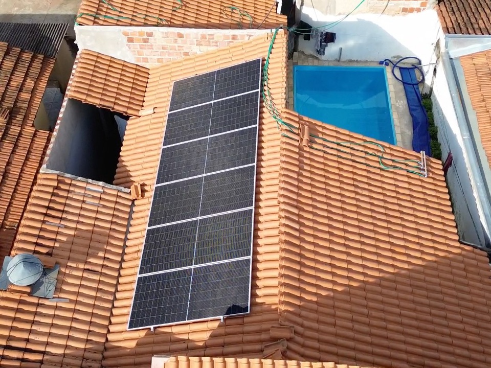 Placas solares em fileira no telhado de telha cerâmica de uma casa, vistas de drone